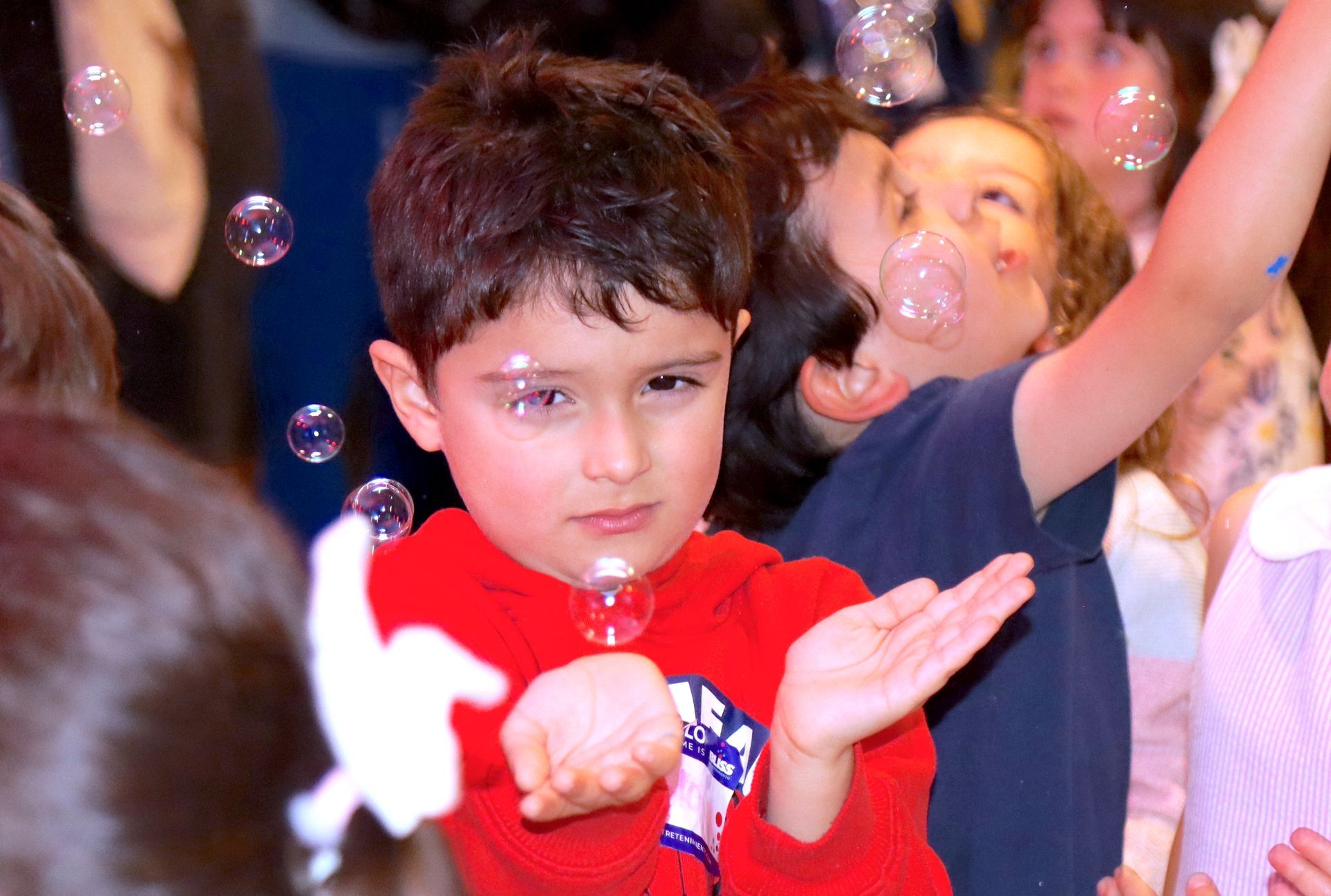 Un niño con una camisa roja está jugando con pompas de jabón.