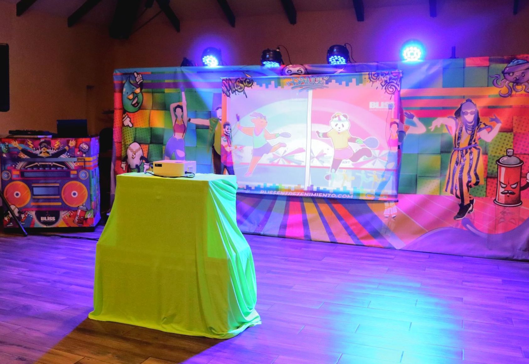 Un escenario con una pantalla de proyección y una mesa delante de ella.