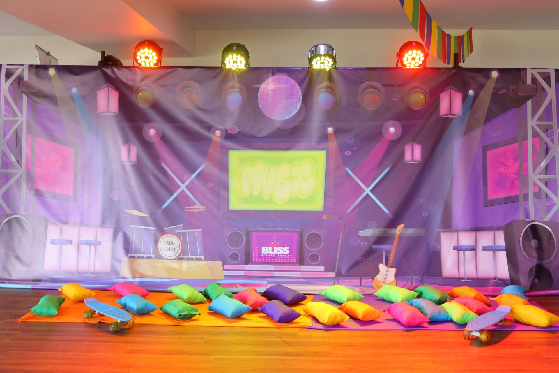 Hay muchas almohadas de colores en el suelo delante de un escenario.