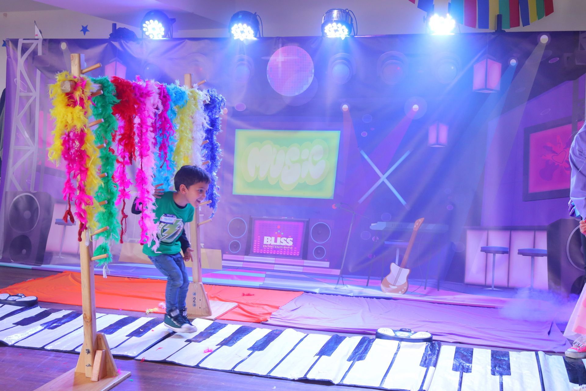 Un niño pequeño está saltando sobre un teclado de piano gigante en un escenario.