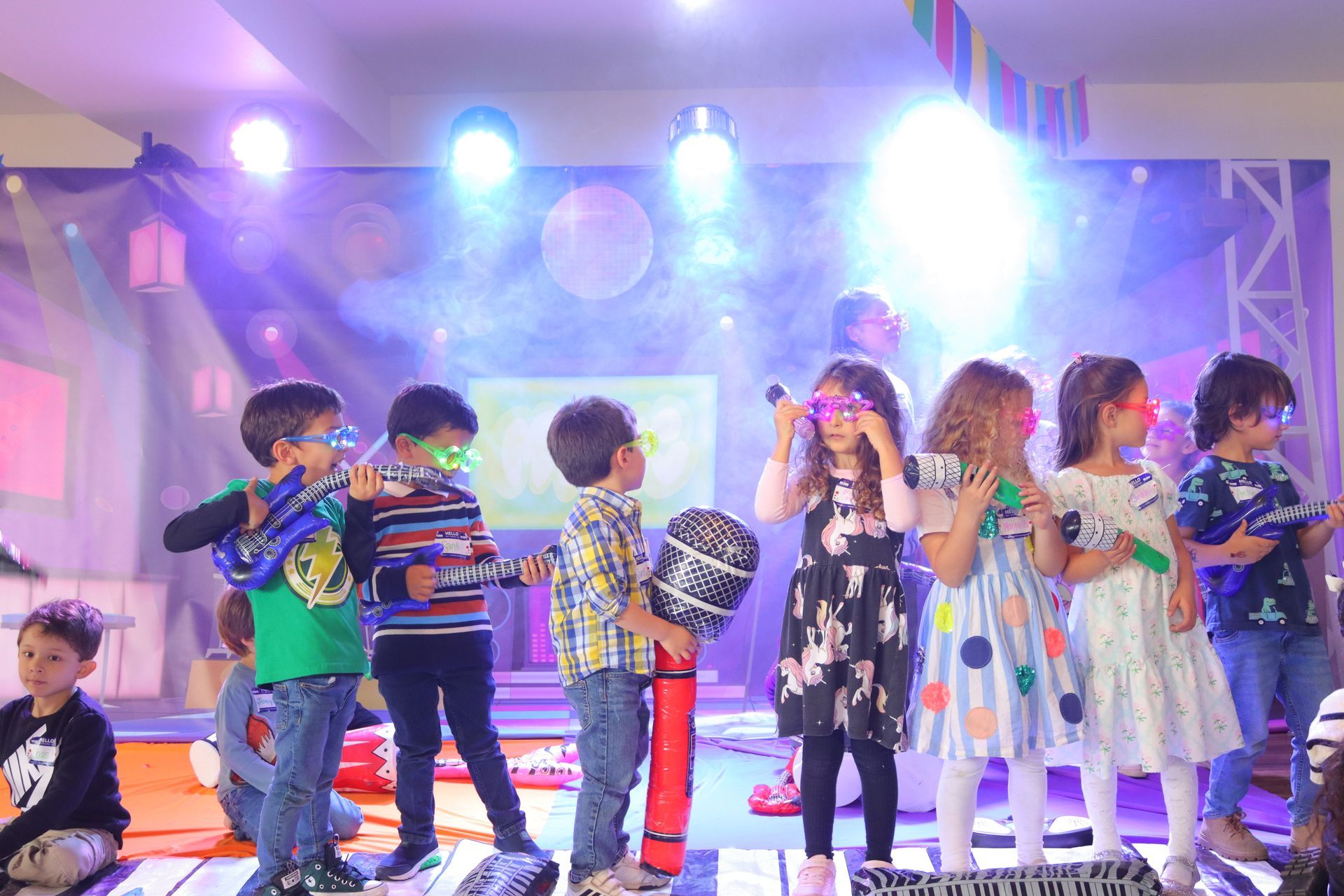 Un grupo de niños está de pie en un escenario frente a un micrófono.