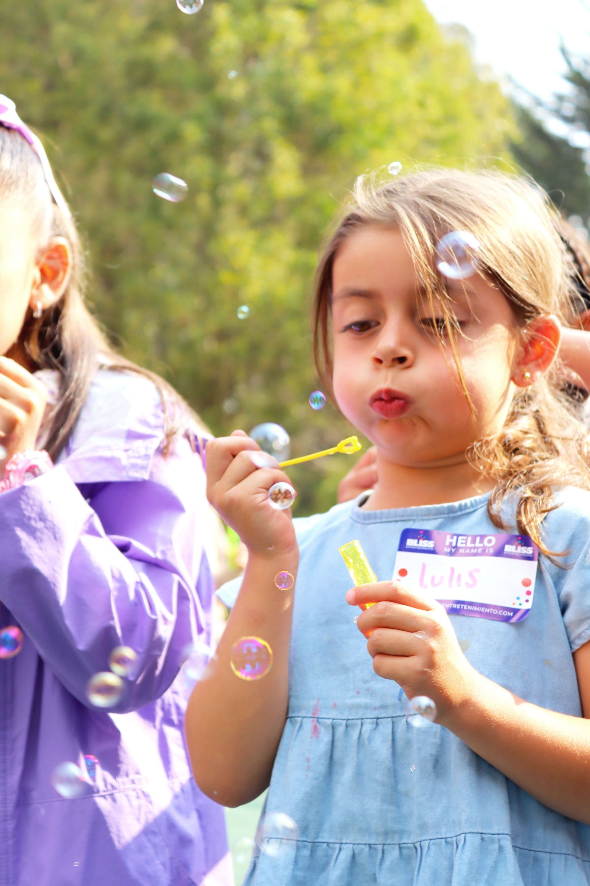 Dos niñas están soplando burbujas de jabón en un parque.