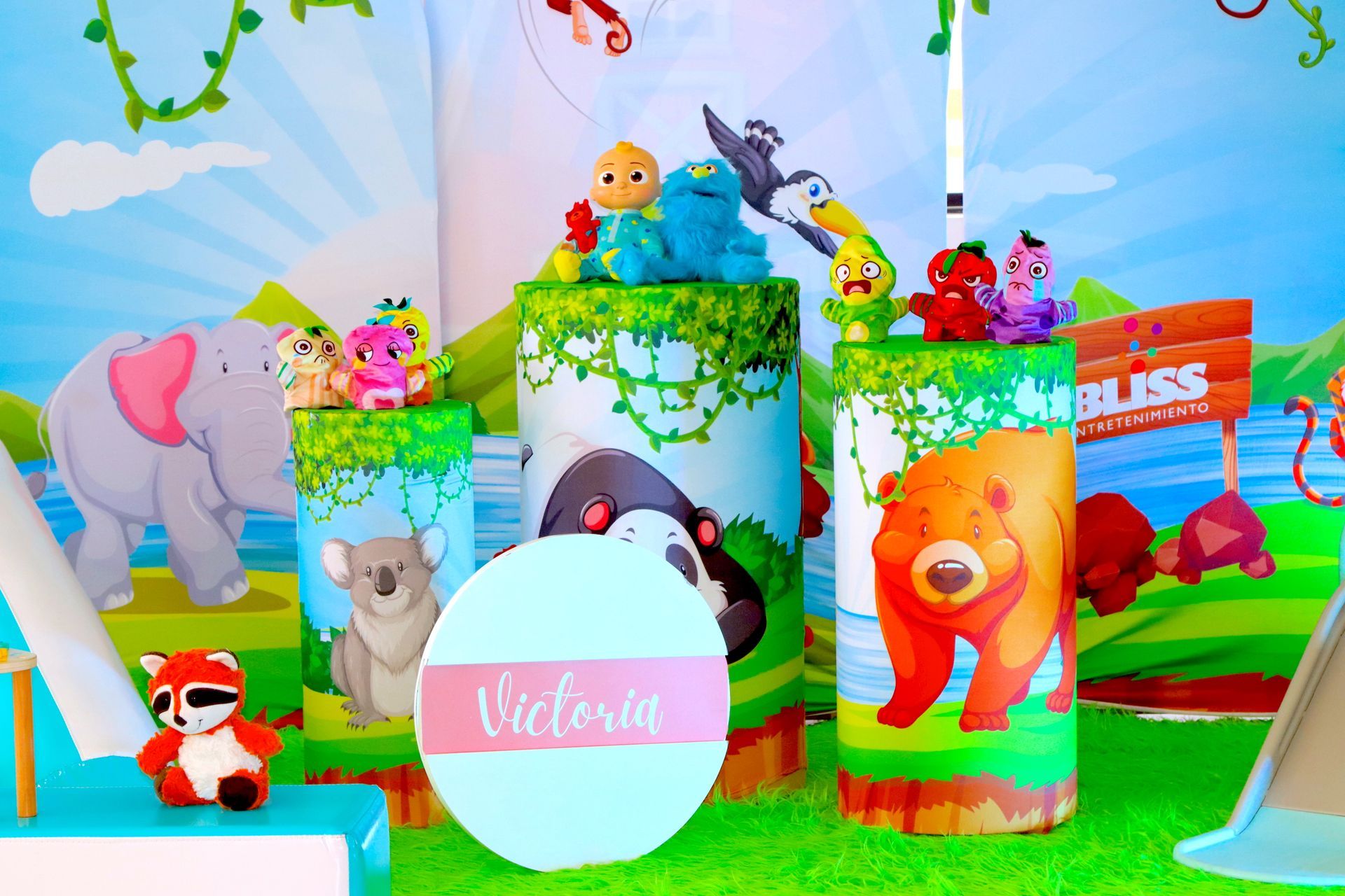Una decoración de fiesta de cumpleaños con animales y un círculo con el nombre Victoria.