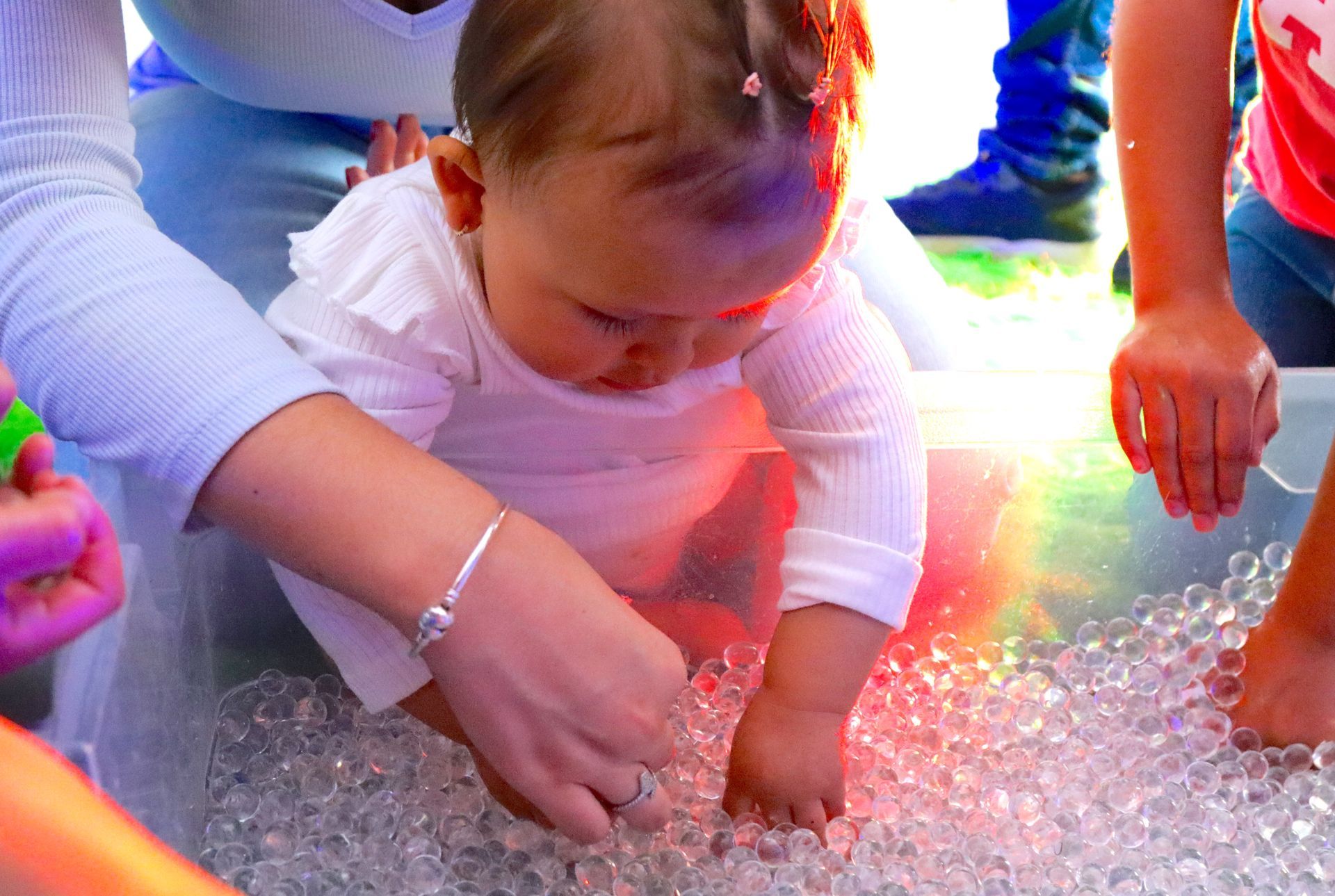 Un bebé está jugando con burbujas en un contenedor sensorial.