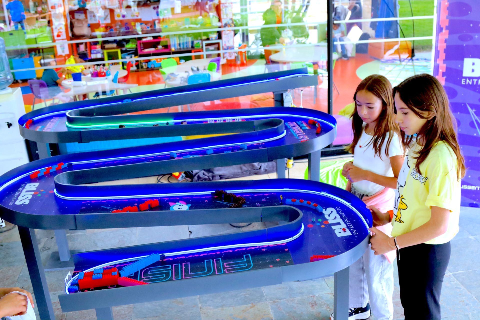Dos niñas están jugando con una pista de carreras de juguete.