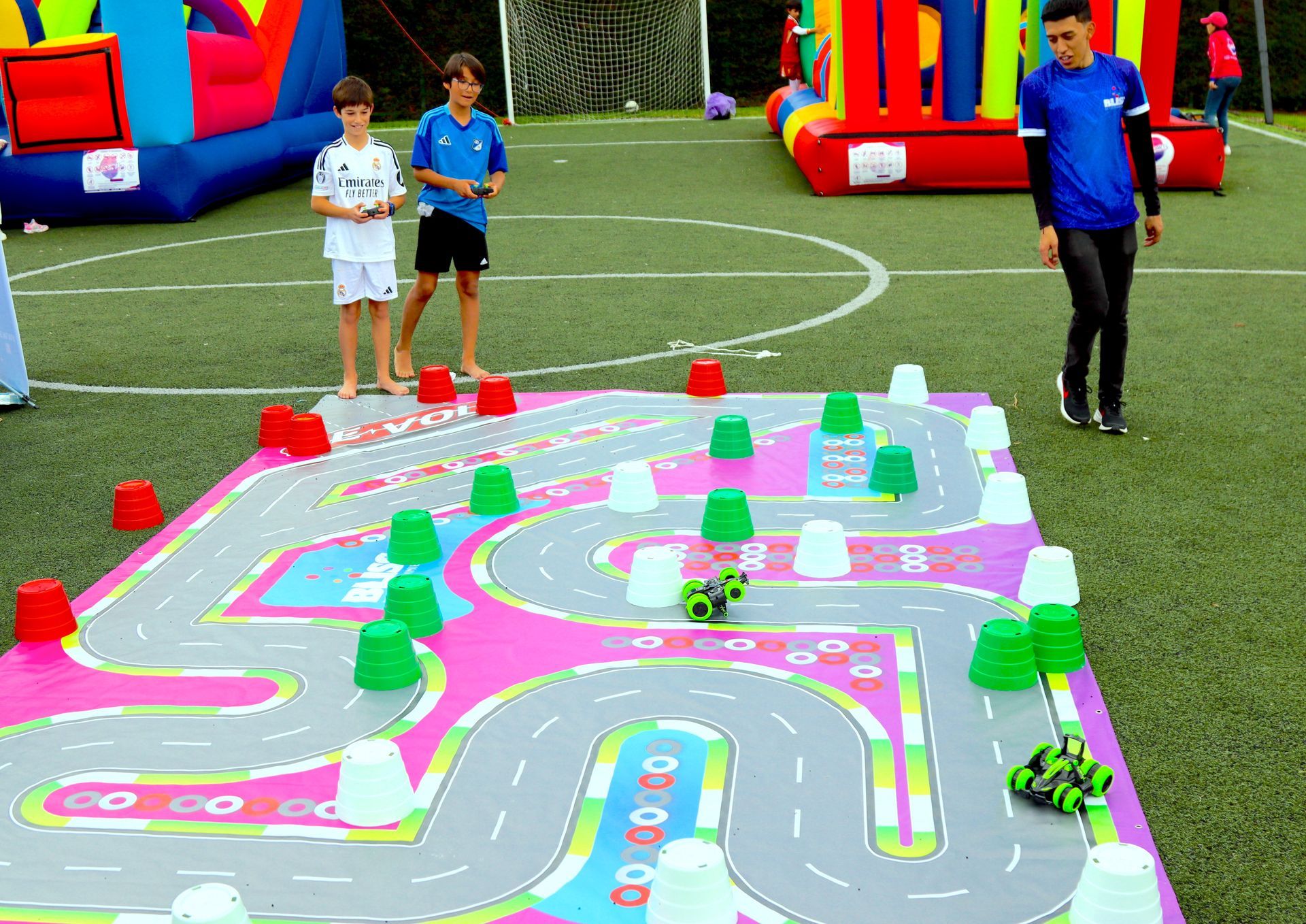Un grupo de niños está jugando con un coche de control remoto en una pista.