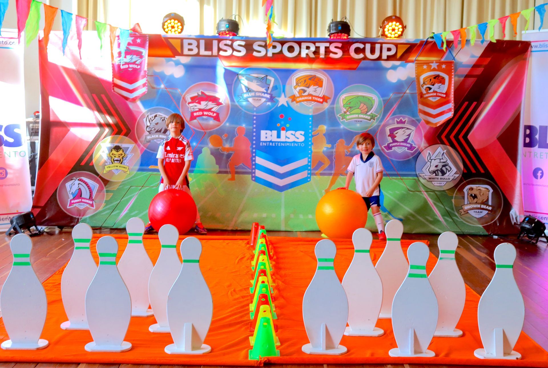 Dos niños están jugando a los bolos en una habitación con bolos