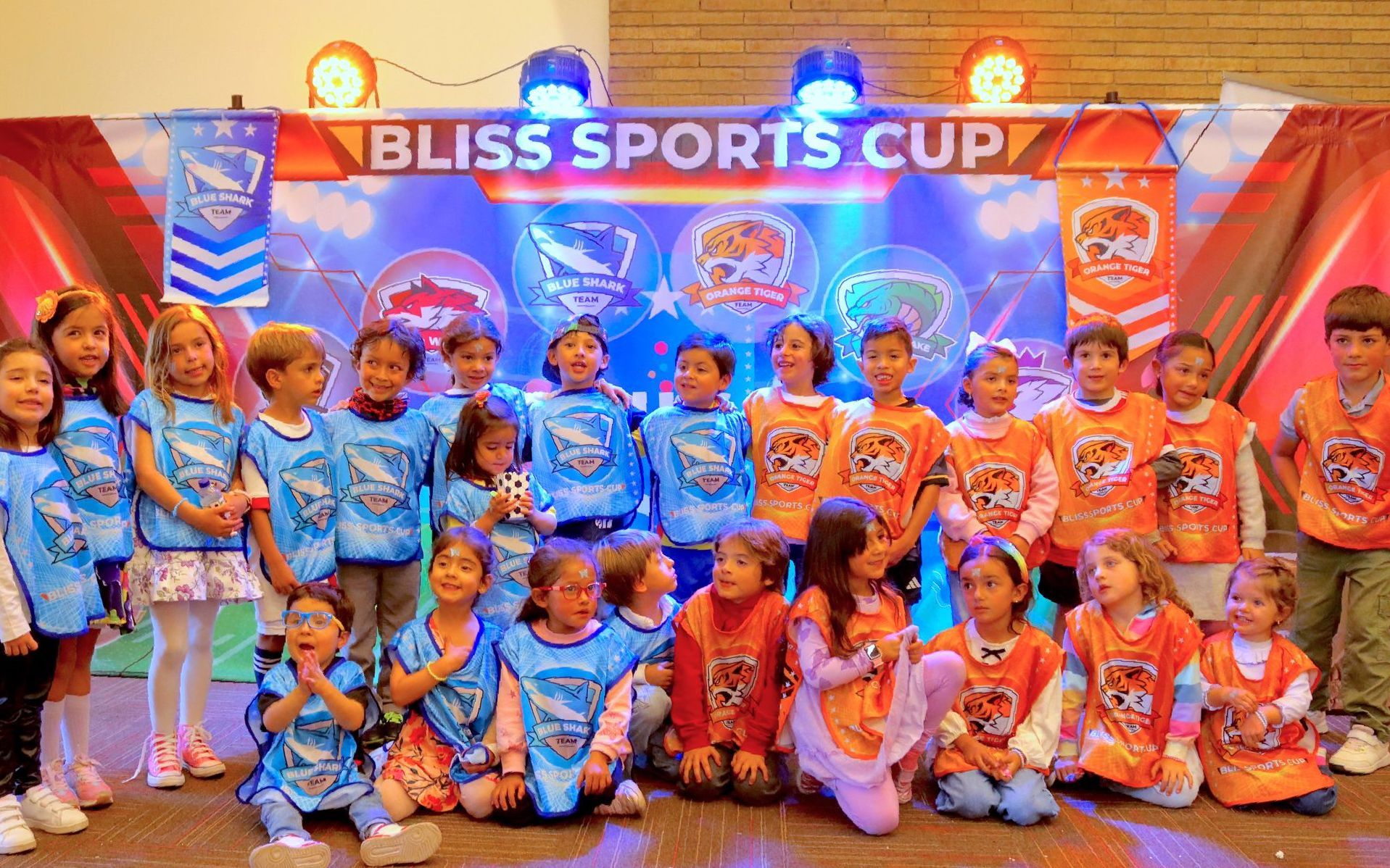 Un grupo de niños posa para una fotografía frente a una pancarta de la Copa Bliss Sports.