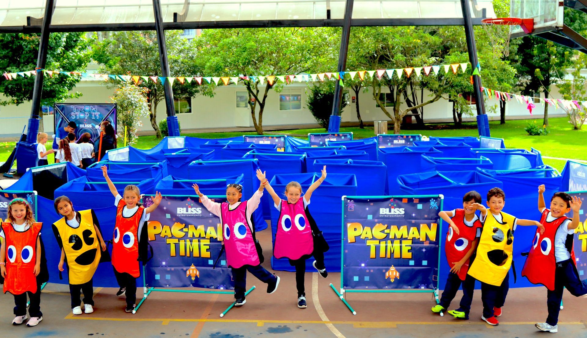 Un grupo de niños vestidos con disfraces de Pacman están parados frente a un laberinto.
