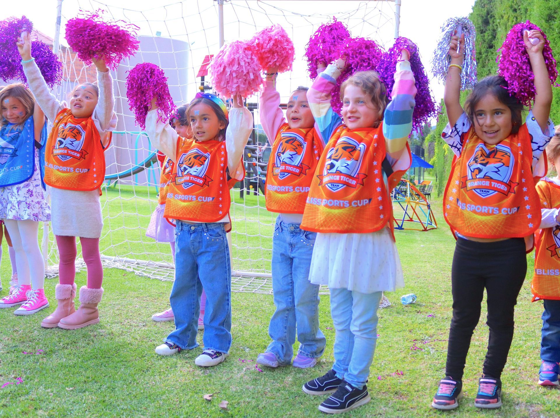 Un grupo de chicas jóvenes que llevan chalecos naranjas con la palabra tigres en ellos.