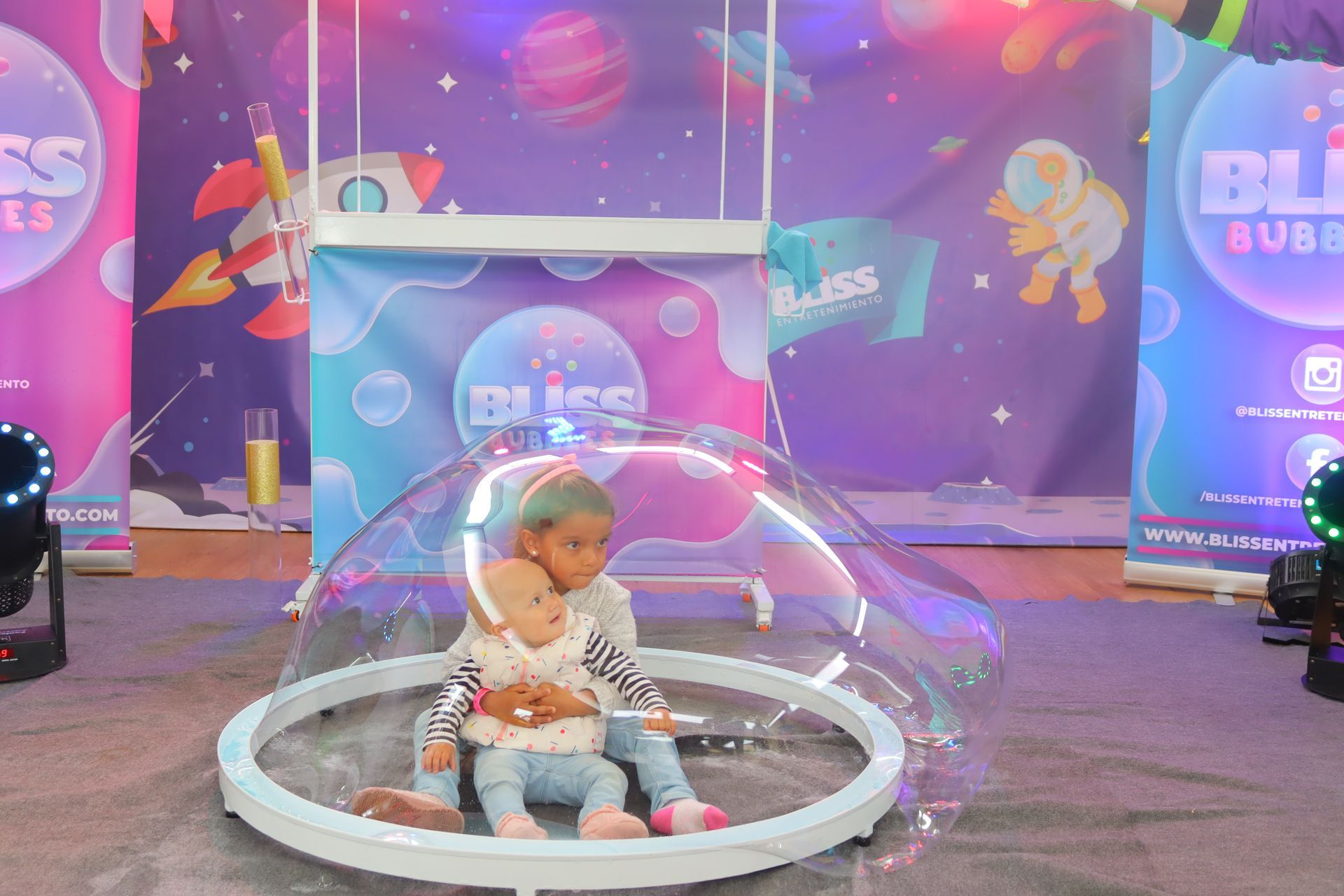 Una niña está sentada dentro de una burbuja de jabón gigante.
