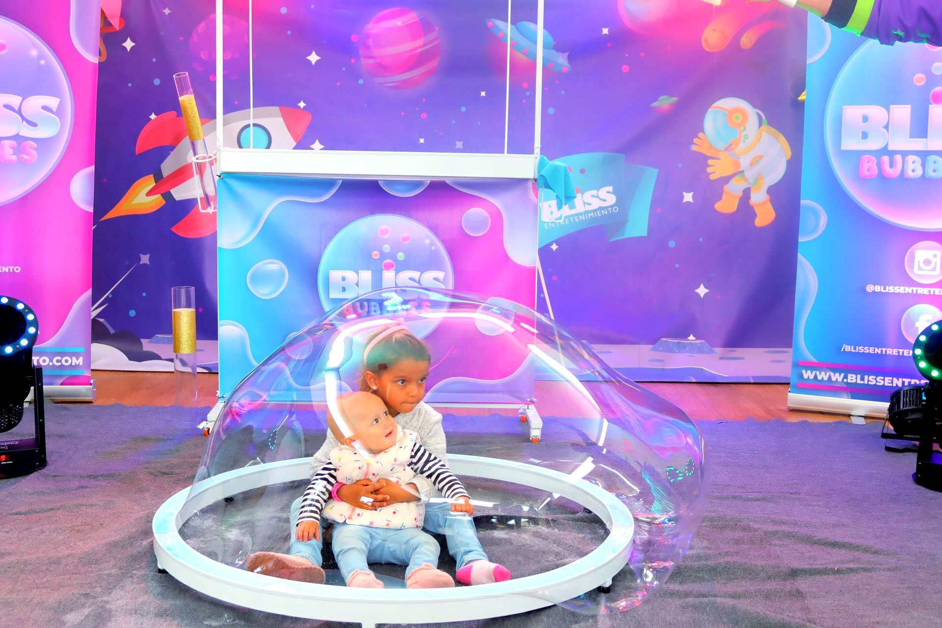 Un bebé y una muñeca están sentados dentro de una burbuja de jabón.