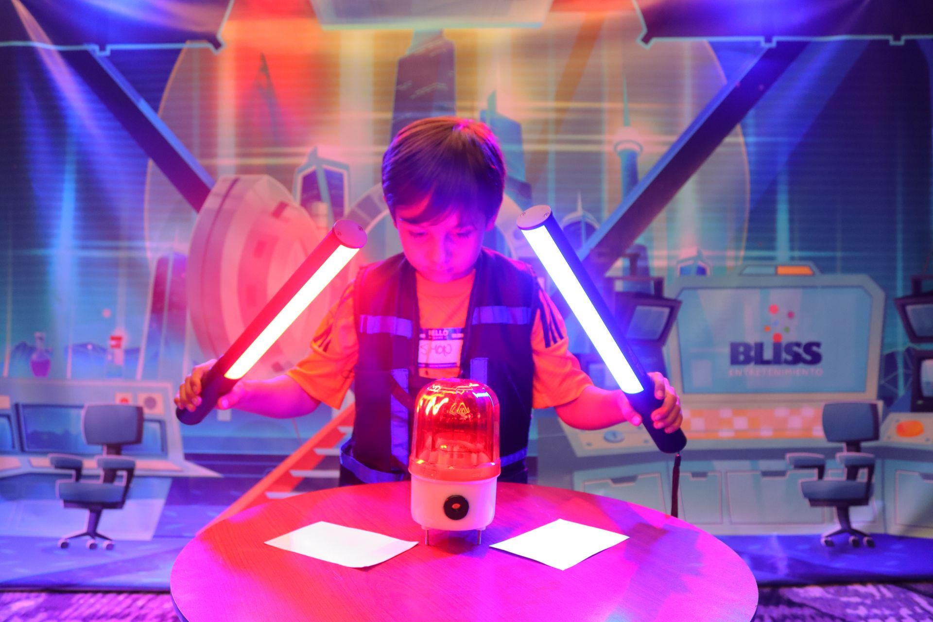 Un niño sostiene dos sables de luz frente a una mesa.
