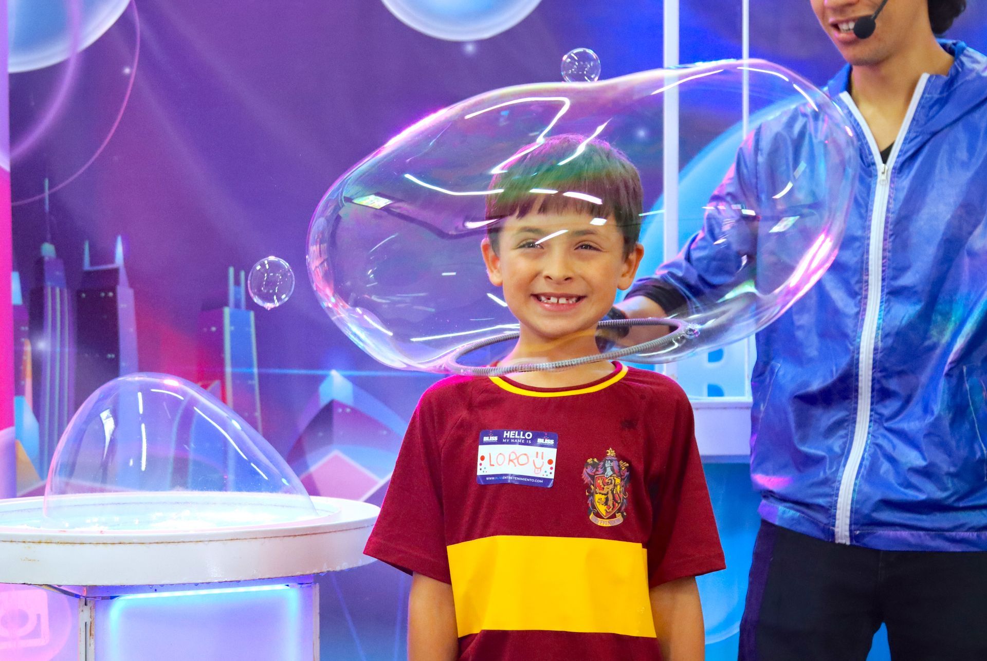 Un niño pequeño con una camiseta de Harry Potter está parado frente a una gran burbuja de jabón.