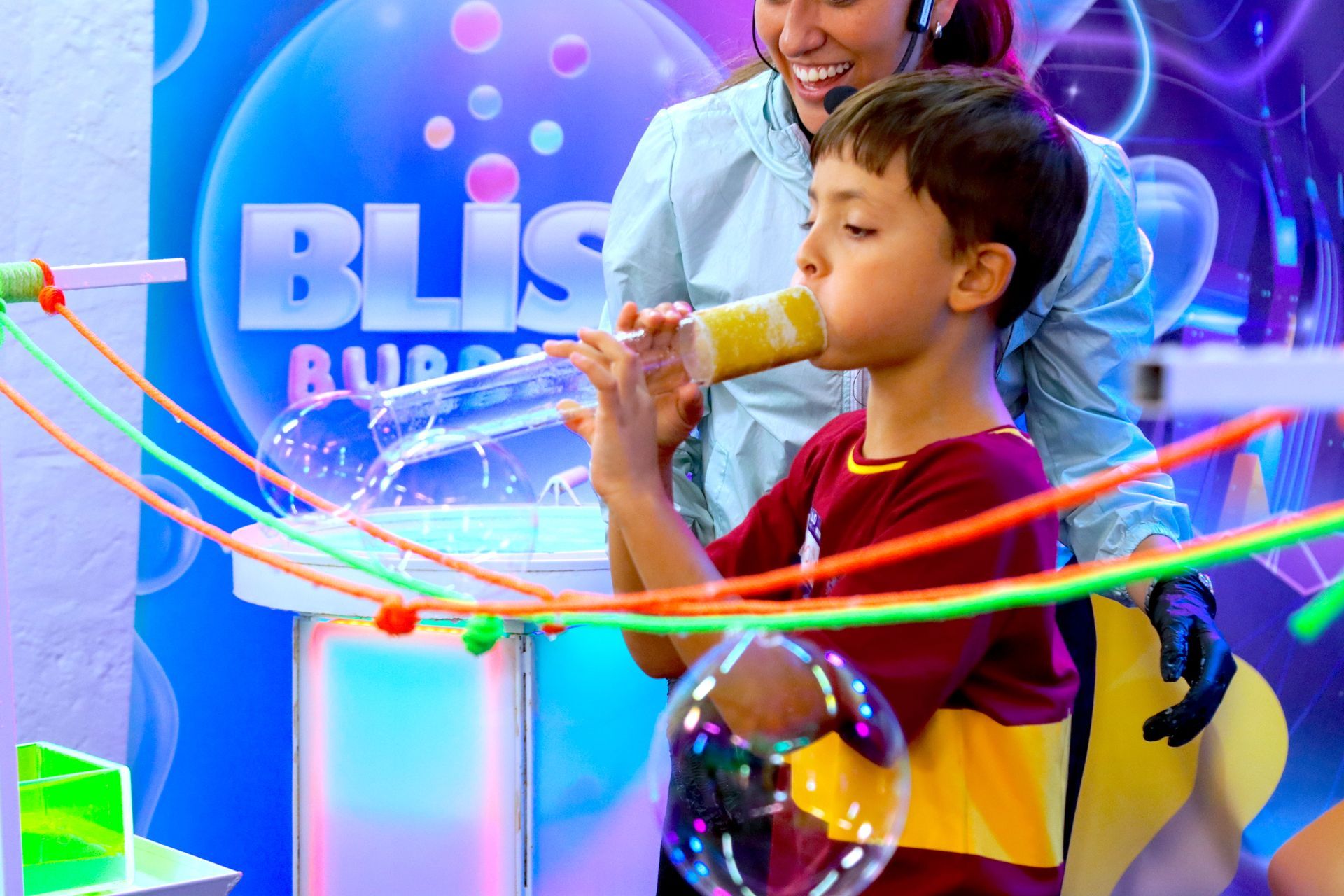 Un niño pequeño está soplando burbujas de jabón mientras una mujer observa.