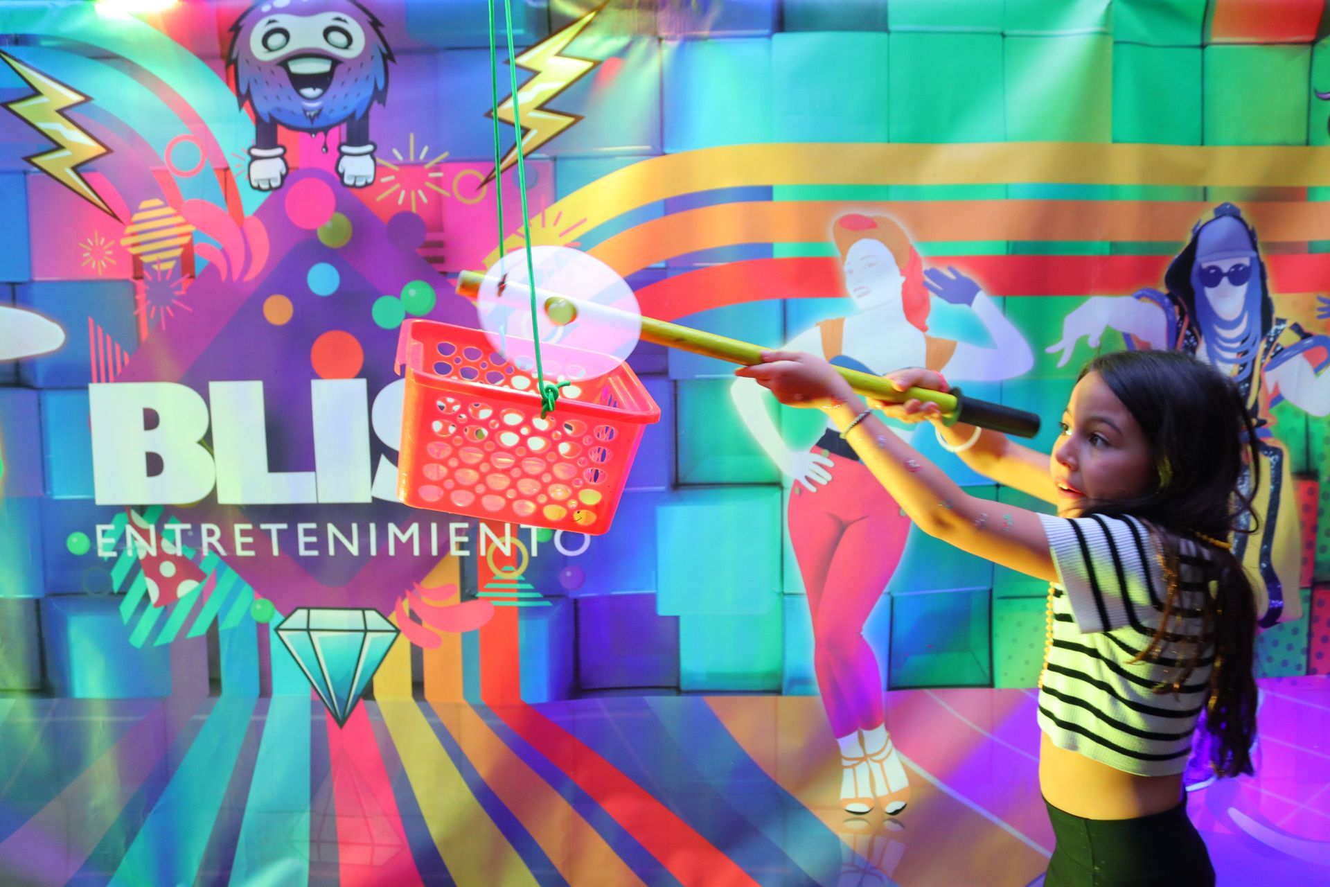 Una niña está jugando un juego frente a una pared colorida.