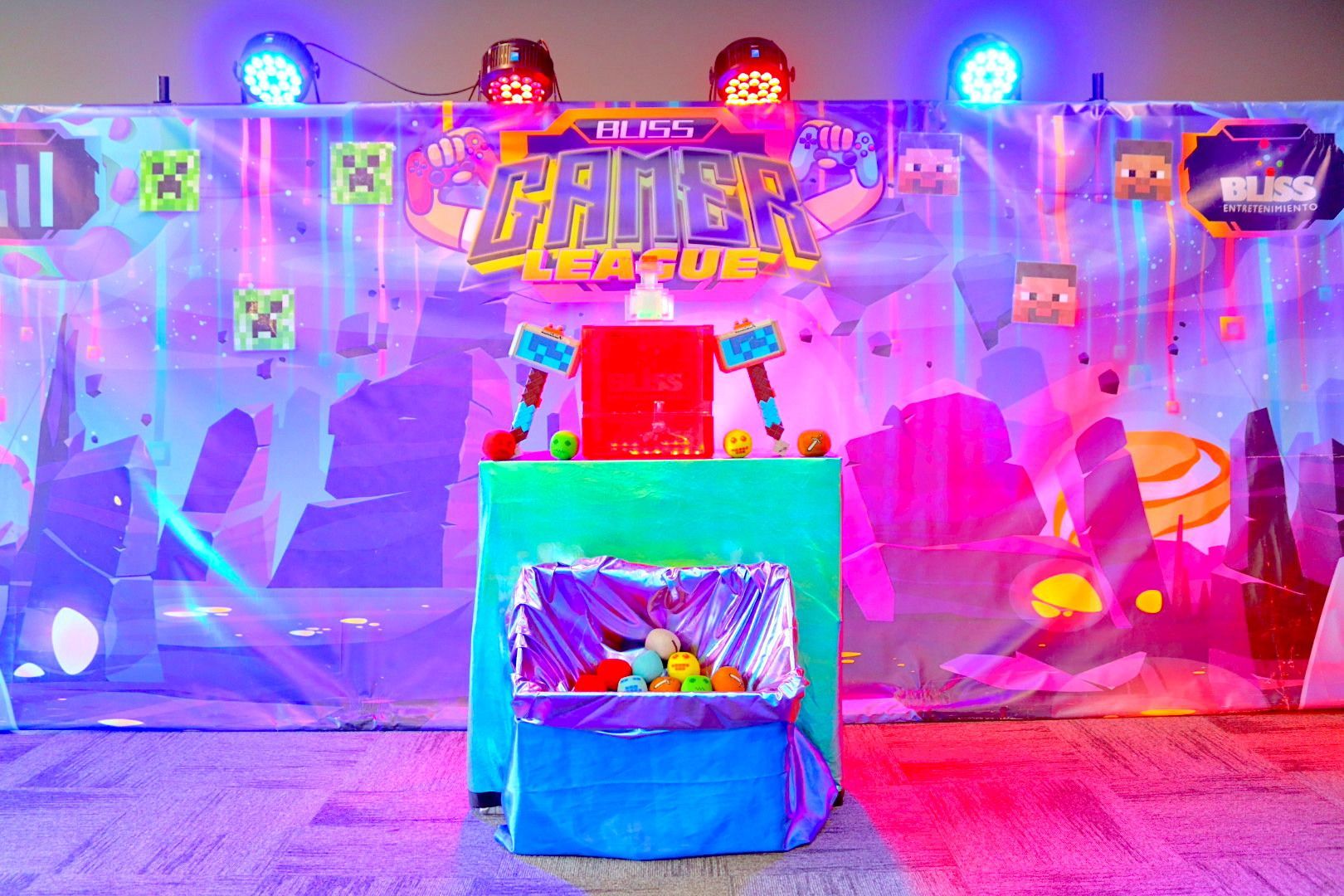 Una mesa con un cubo de pelotas frente a una pared con temática de Minecraft.