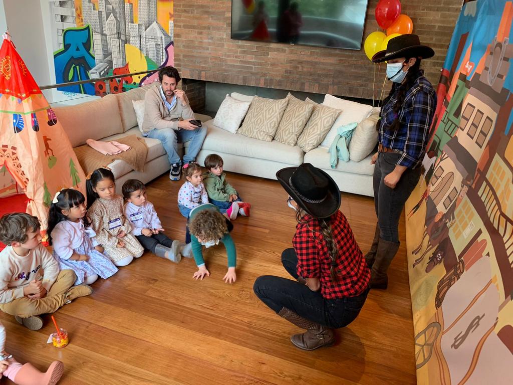 Un grupo de niños está sentado en el suelo en una sala de estar.