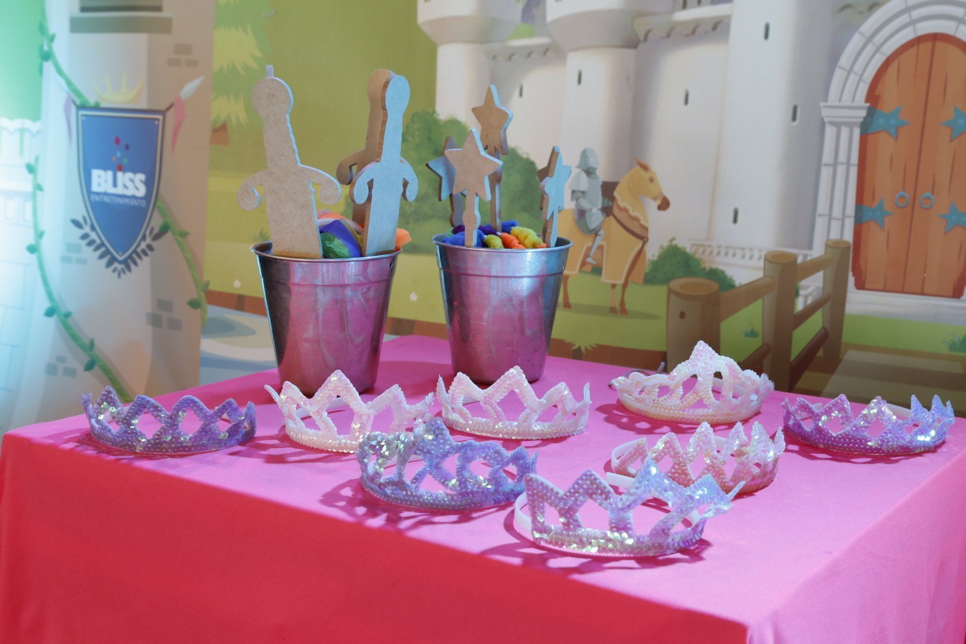 Una mesa con un mantel rosa y coronas sobre ella.