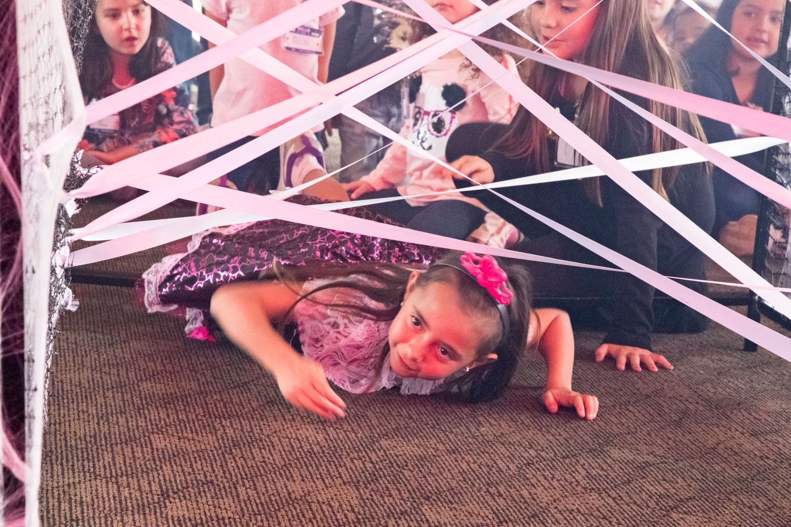 Una niña está acostada en el suelo cubierta con una cinta rosa.