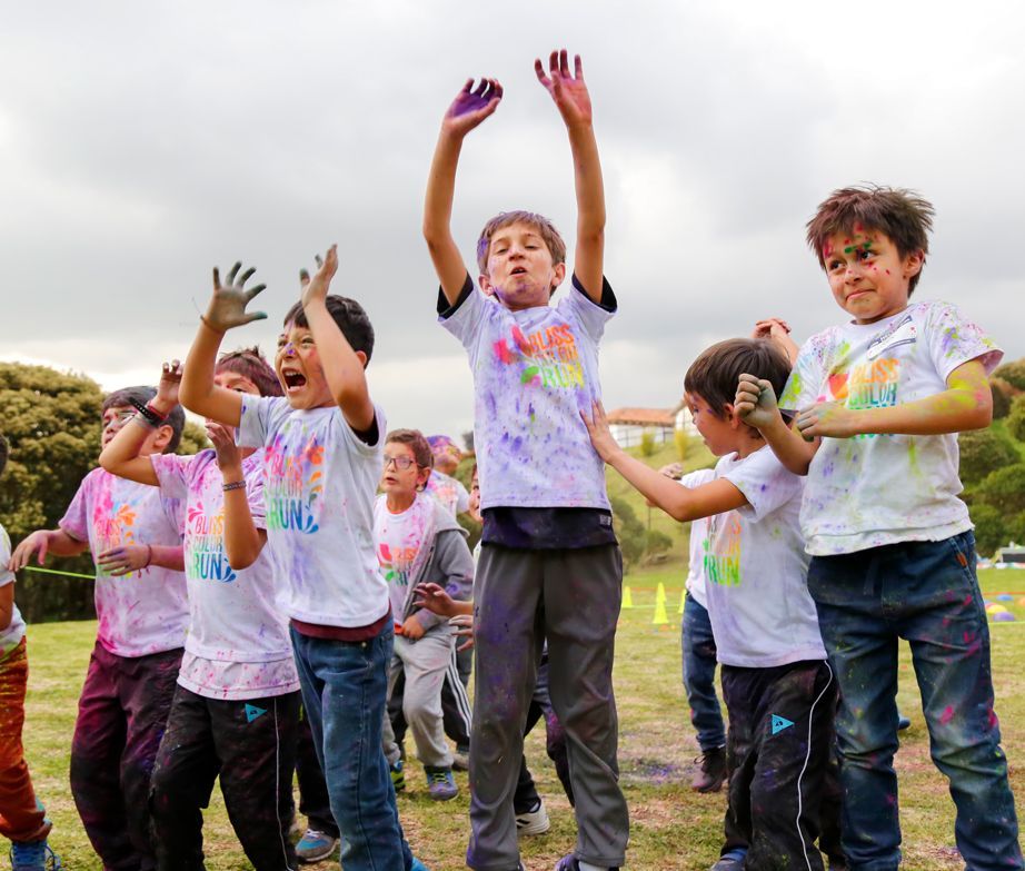Niños cubiertos de polvos de colores celebran al aire libre.
