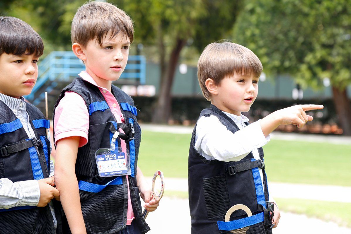 Tres niños pequeños están parados uno al lado del otro en un parque.