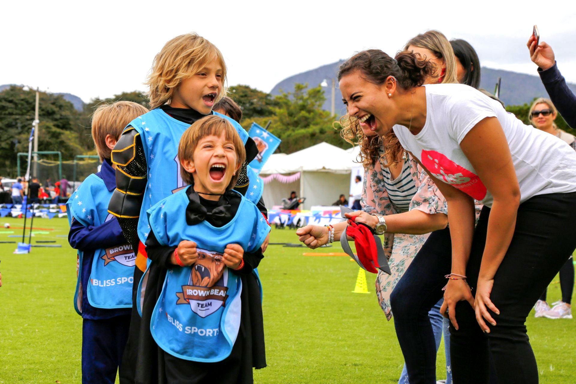 Una mujer se ríe con un grupo de niños en un campo.