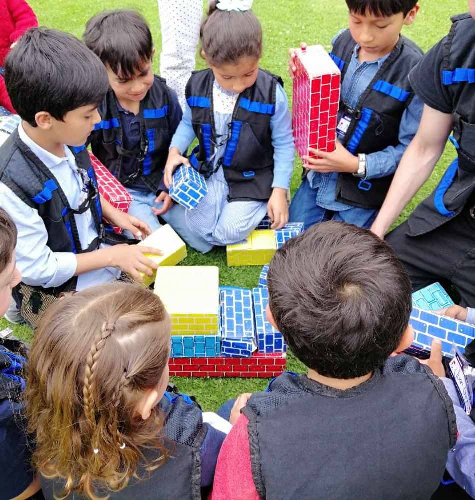 Un grupo de niños está sentado en el césped jugando con bloques.