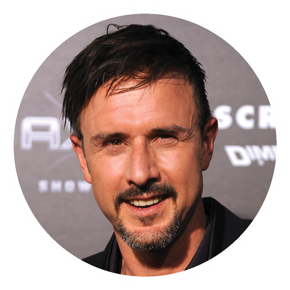 David Arquette smiling, headshot, against a dark backdrop.