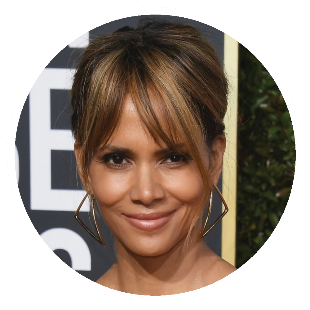 Halle Berry with brown hair and bangs wearing large gold earrings, smiling.