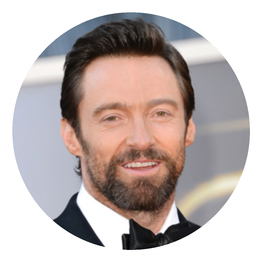 Hugh Jackman smiling, wearing a black tuxedo, with a well-groomed beard.