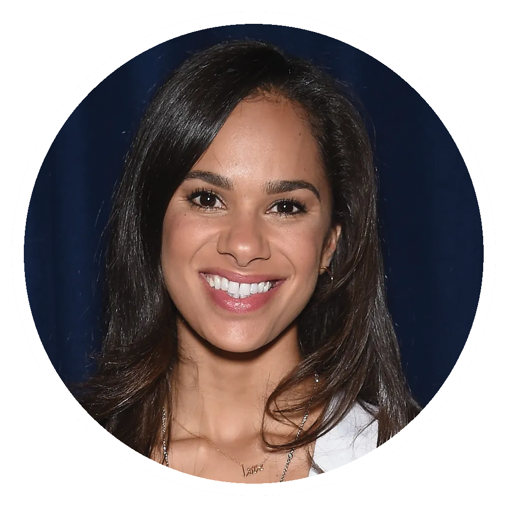 Misty Copeland with dark hair smiles, wearing necklace, set against a dark background.