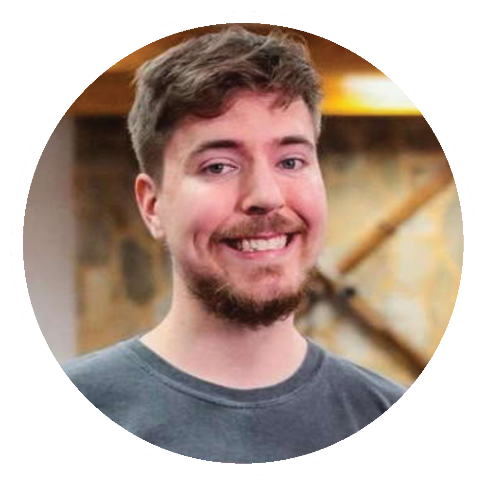 MrBeast smiles, wearing a gray t-shirt. Dark, short hair and a beard. Background: a stone wall and wood.