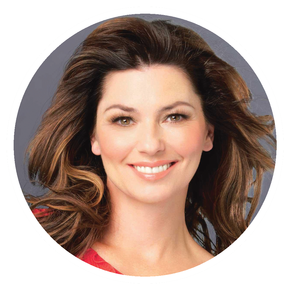 Shania Twain smiles, brown hair styled, red shirt, set against a gray background.