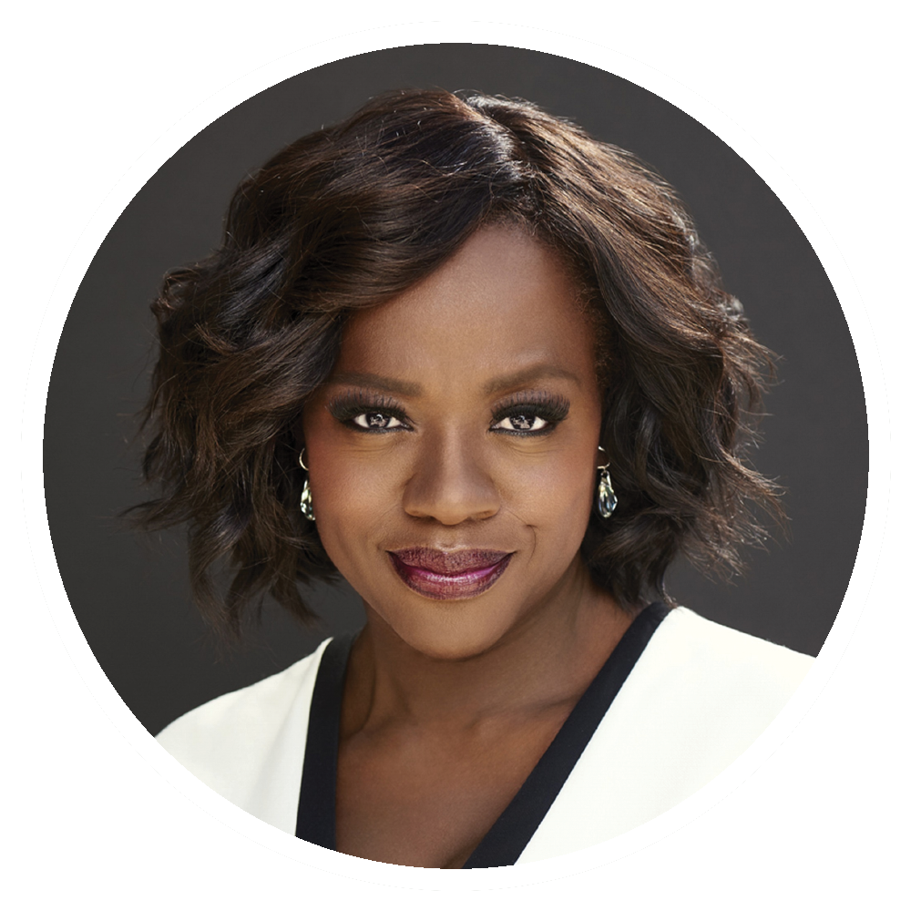 Viola Davis smiles; wearing a white and black top, with dark short hair and earrings.