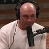 A bald man wearing headphones is talking into a microphone.