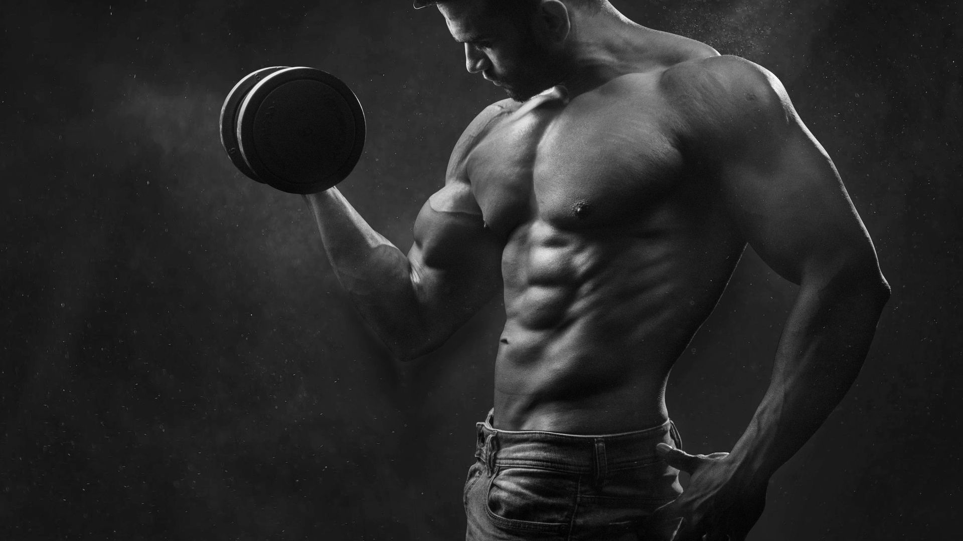A shirtless man is lifting a dumbbell in a black and white photo.