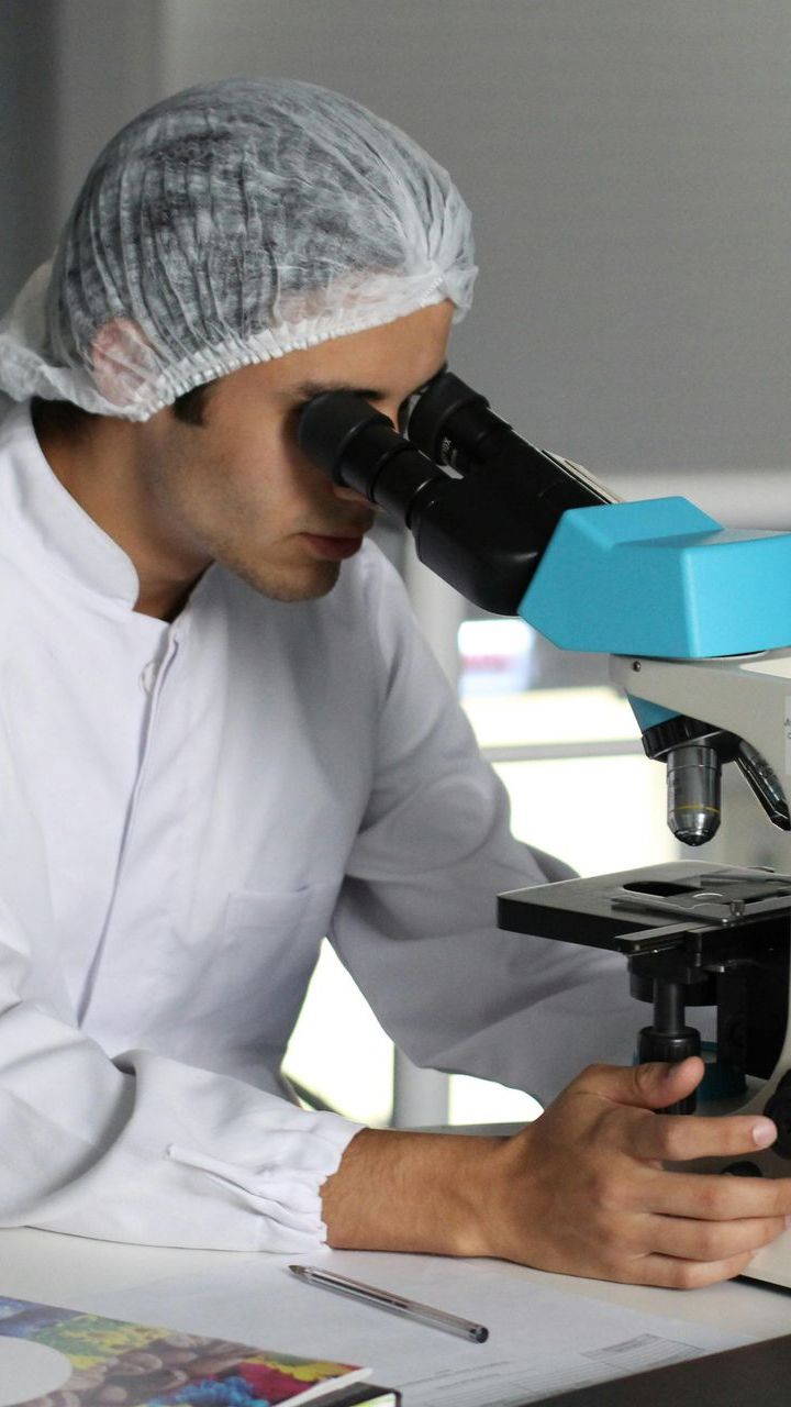 A man is looking through a microscope in a lab.