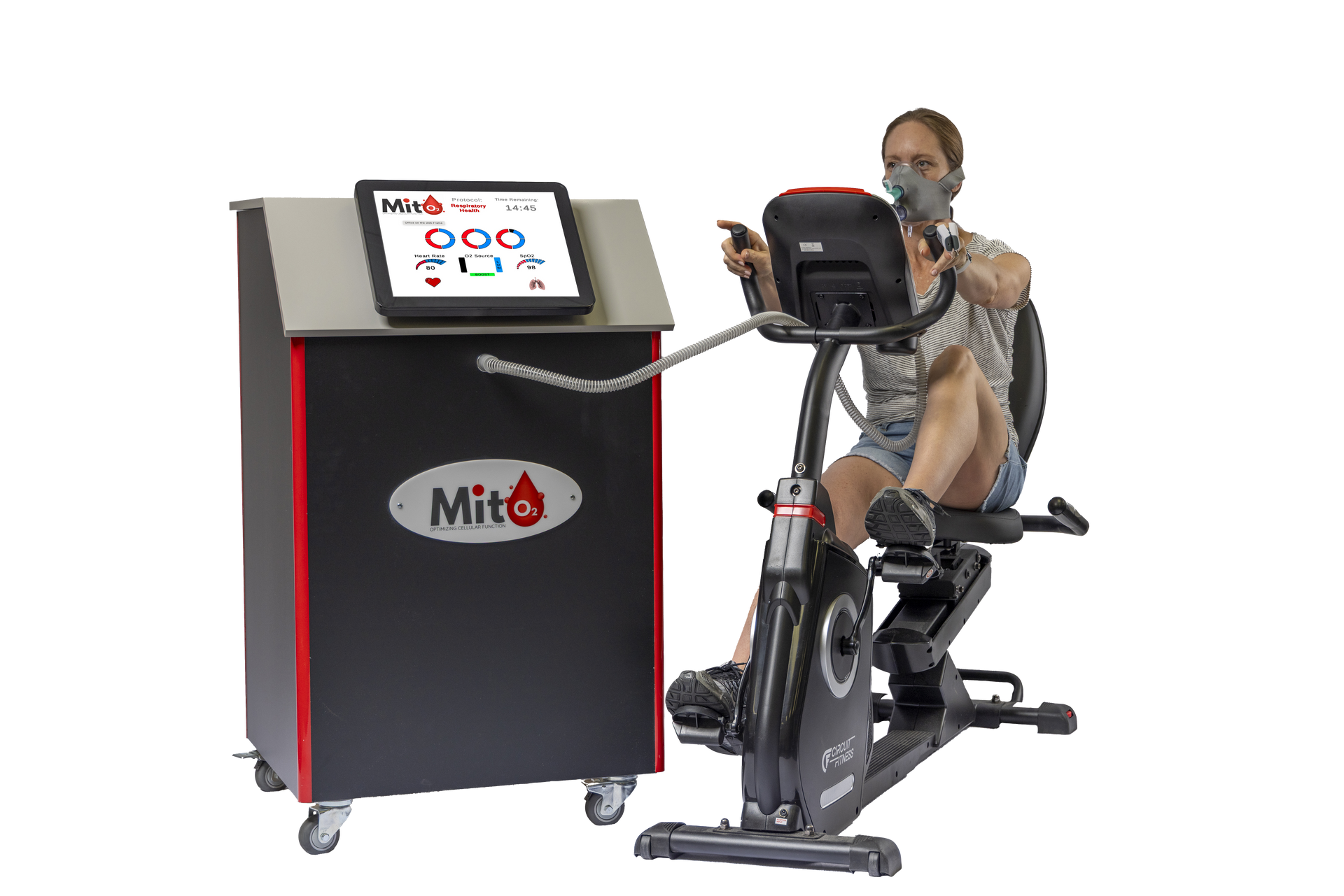 A woman wearing a mask is riding an exercise bike next to a machine.