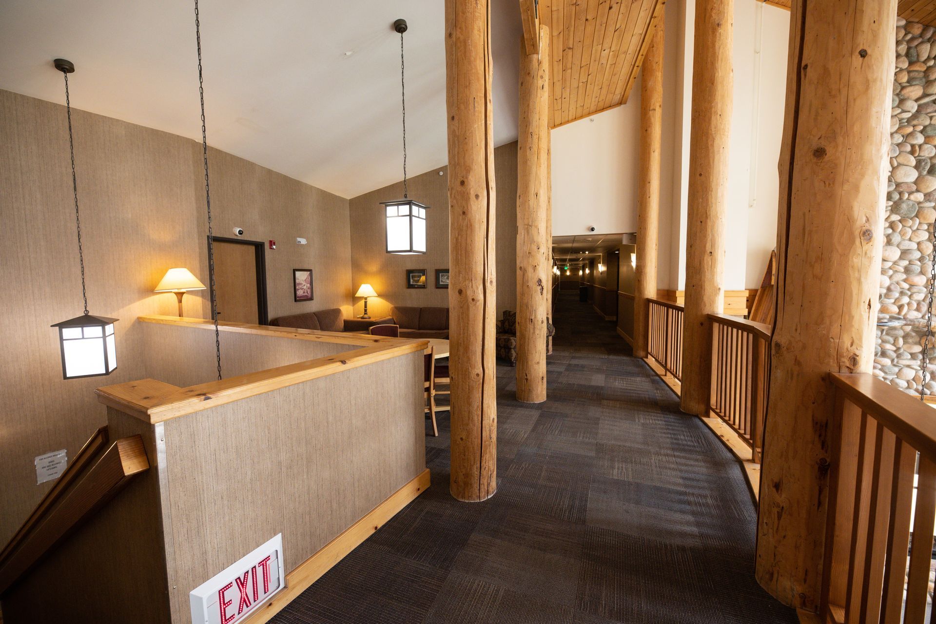 A long hallway with a red exit sign on the wall