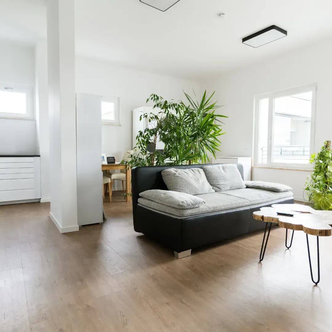 A living room with a black couch and a wooden coffee table.