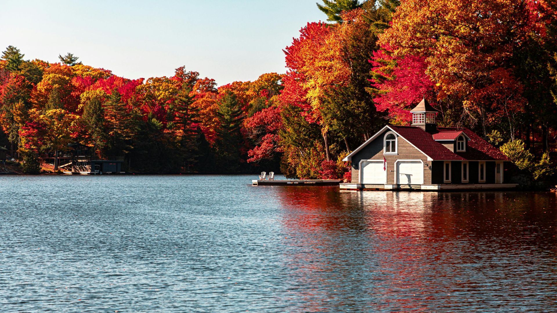 Lake with autumn trees and a red-roofed cottage on the shore
