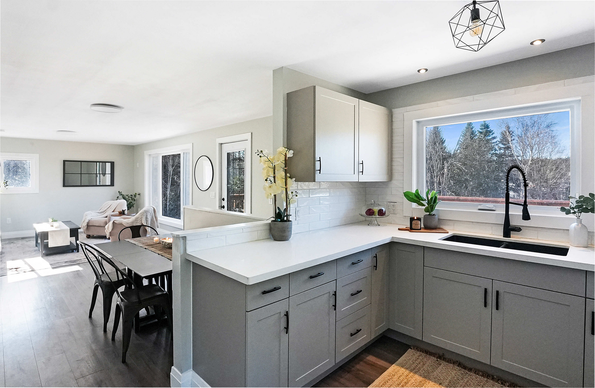 Open-concept kitchen and dining area with gray cabinets, white countertops, and a large window.