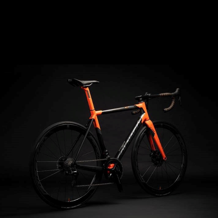 Una bicicletta nera e arancione è parcheggiata al buio.