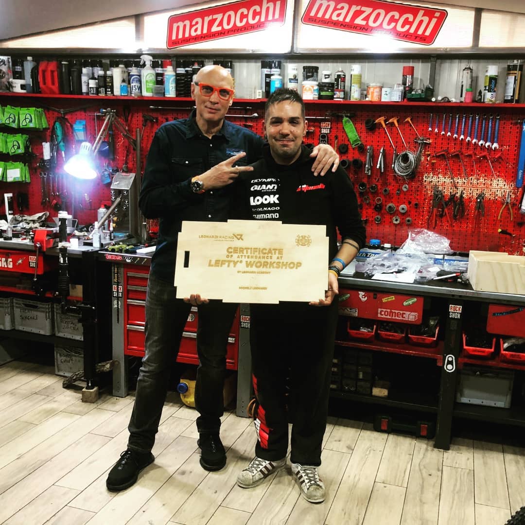 Due uomini sono in piedi uno accanto all'altro in un'officina e tengono in mano una scatola.