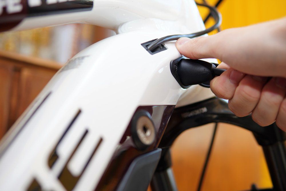 Una persona sta collegando un cavo a una bicicletta elettrica.