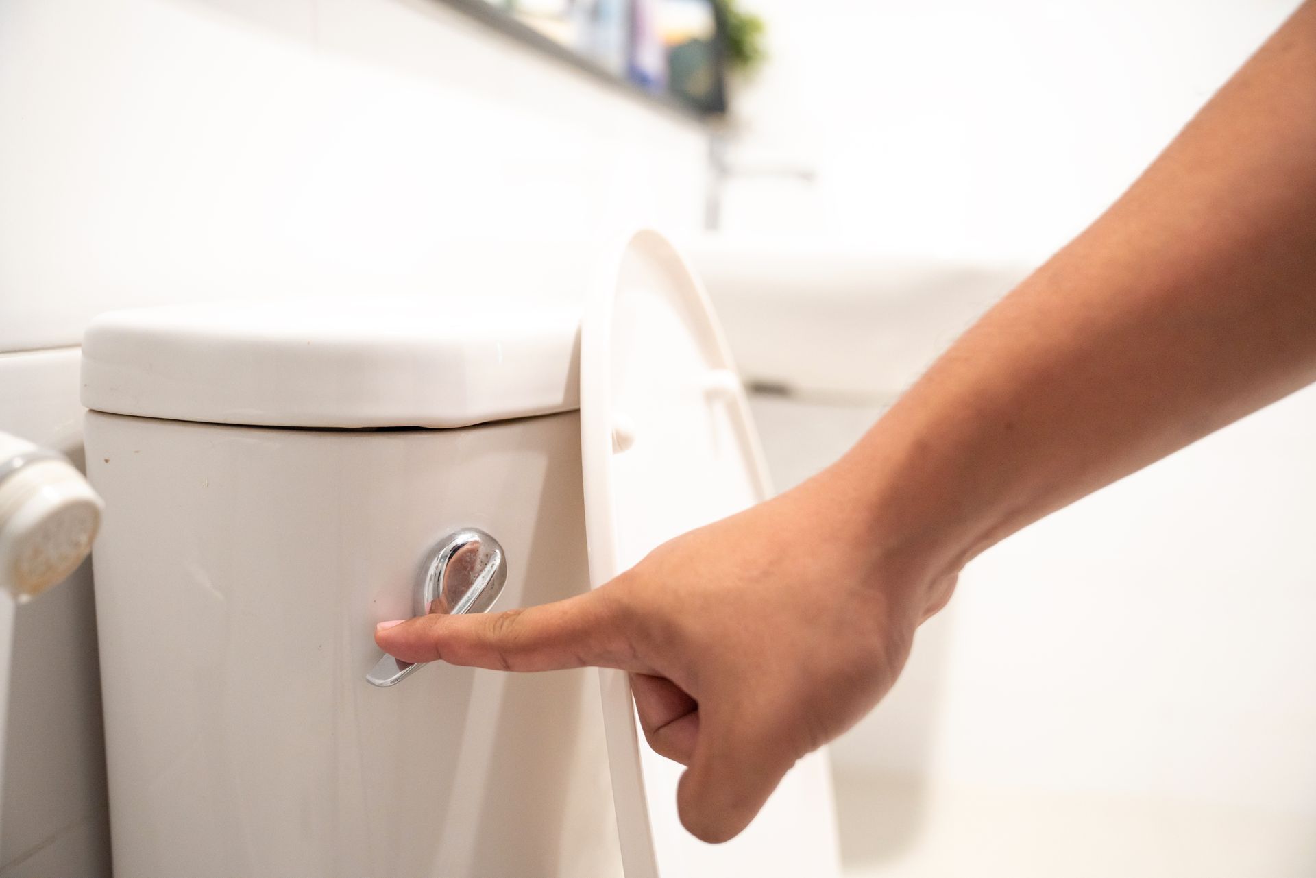 Hand pressing flush handle on toilet for clogged toilet repair service demonstration. 
