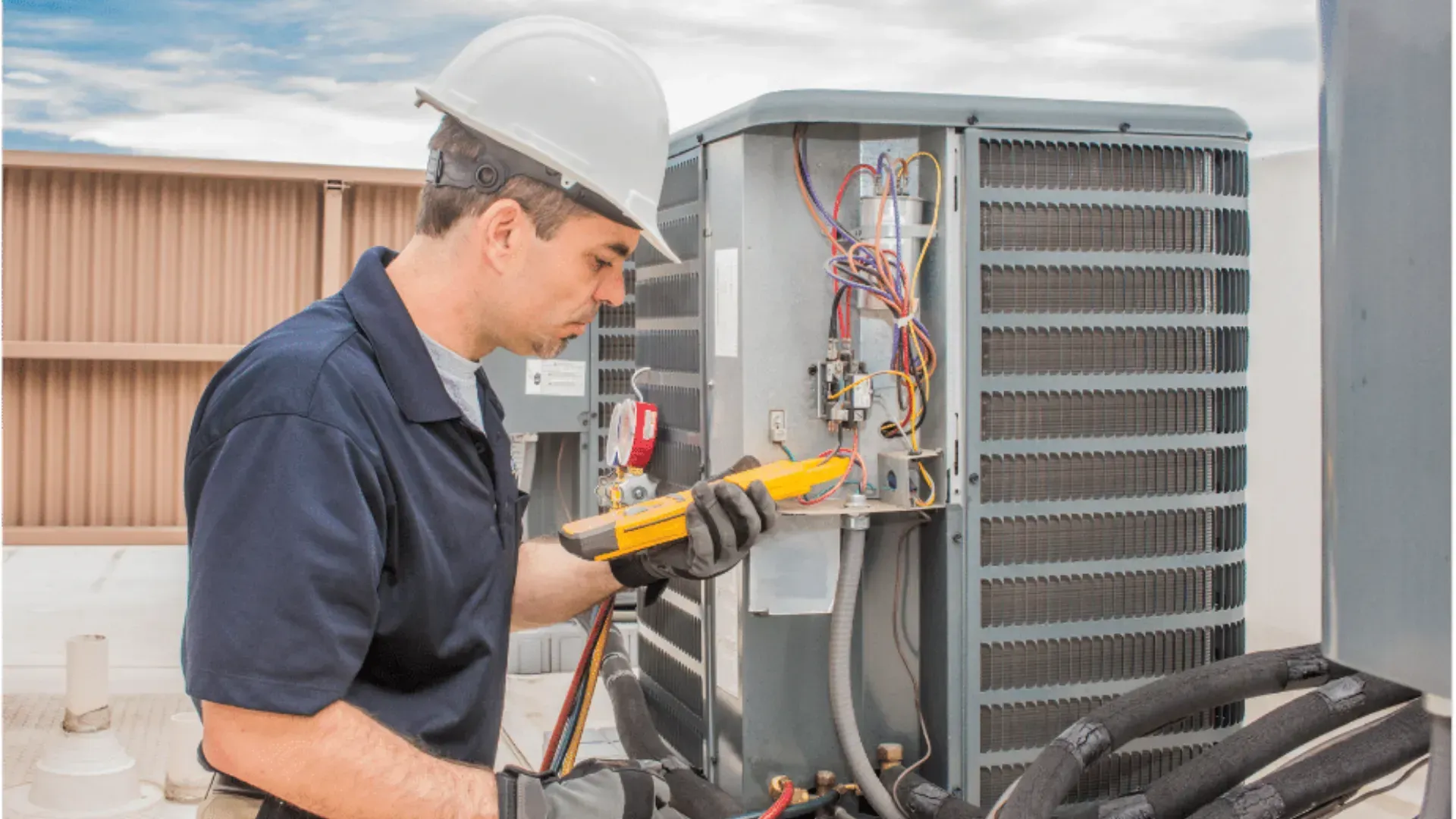 A man in a hard hat is working on an air conditioner.