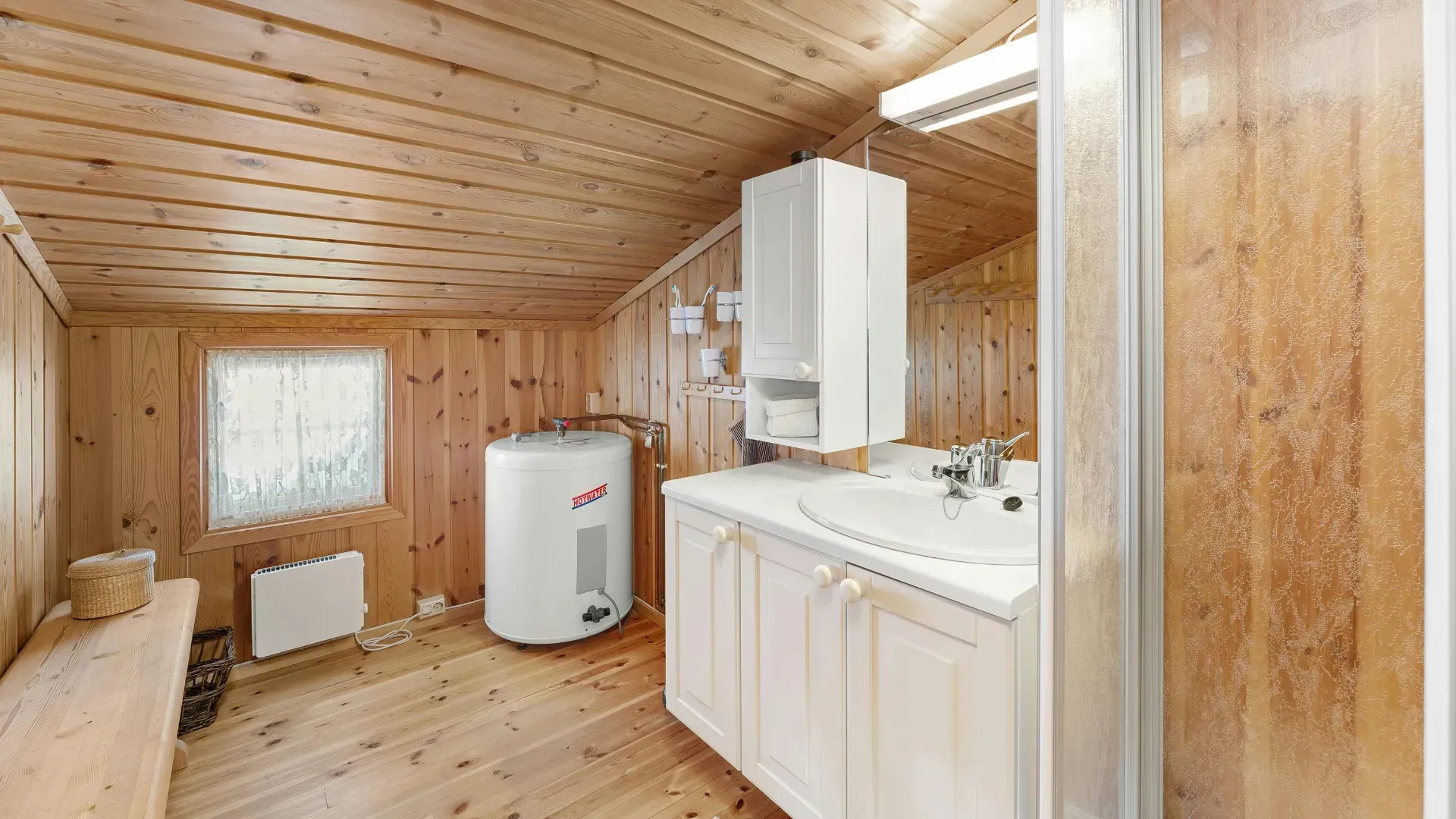 A bathroom with wooden walls , a sink , and a heater.