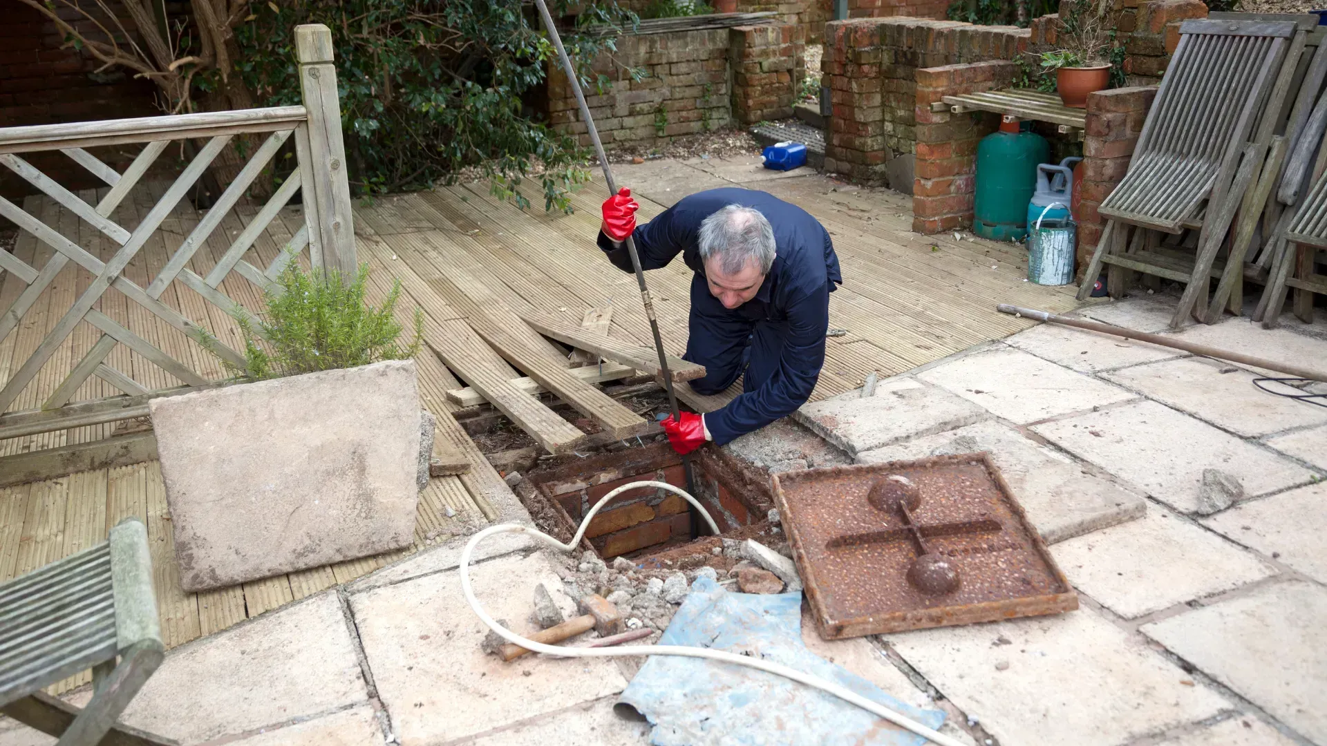 A man is working on a drain on a patio.